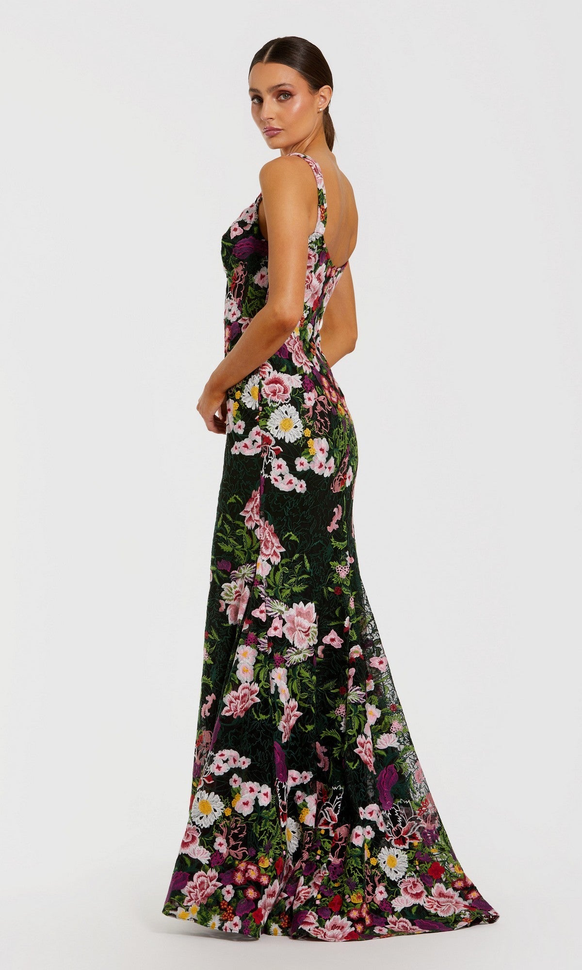 A woman models the Mac Duggal 69004, a long, sleeveless fitted formal dress with elegant floral embroidery, posing against a plain white background and glancing over her shoulder with her hair pulled back.